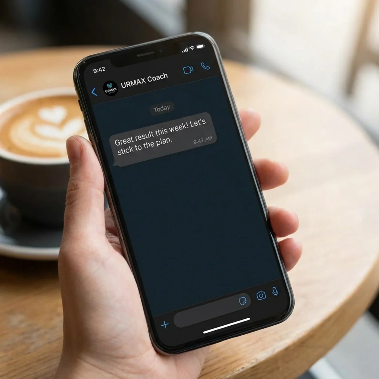 Hand holding smartphone with URMAX Coach chat, health supplement support message visible