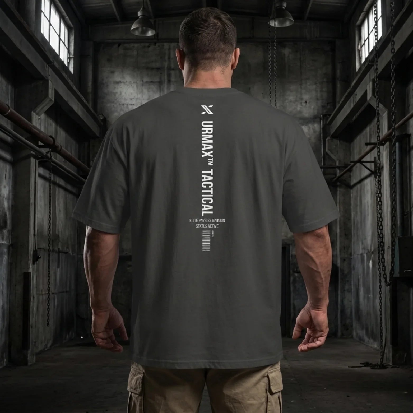 Man in an URMAX tactical oversized t-shirt standing in an industrial gym setting