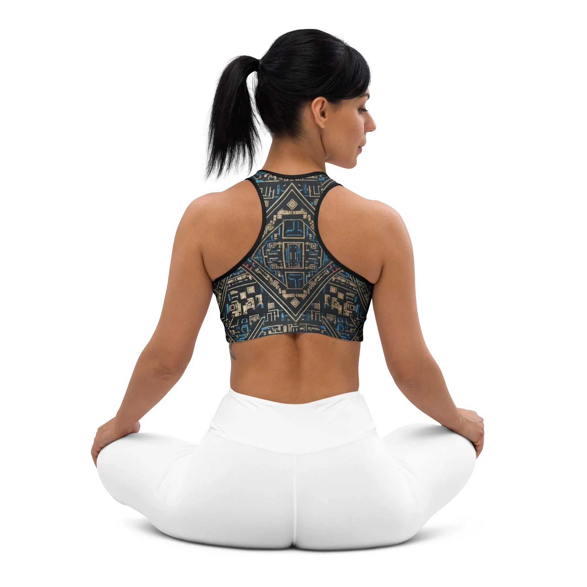 Woman in geometric print sports bra and white leggings sitting cross-legged, urmax fitness apparel