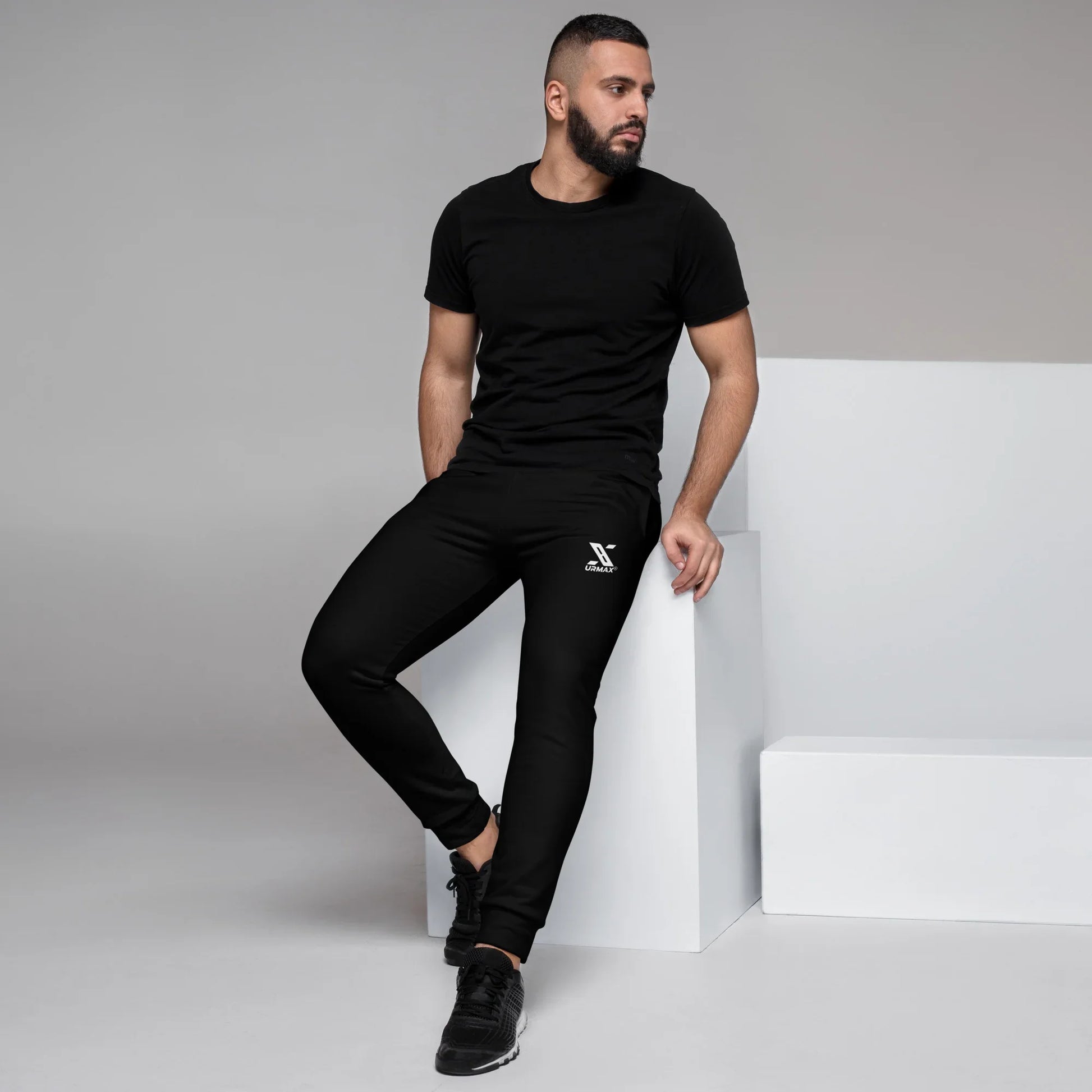 Man wearing black Urmax joggers and t-shirt in modern studio setting