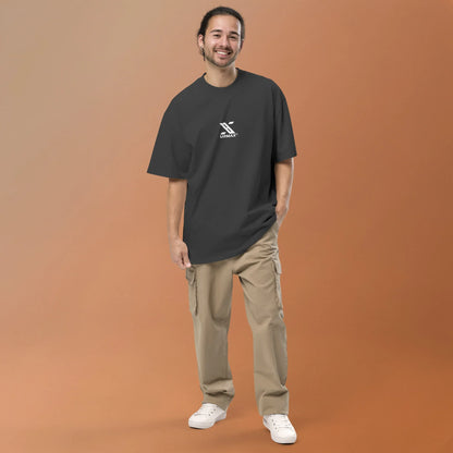 Man in oversized faded black Urmax t-shirt and cargo pants standing on brown background