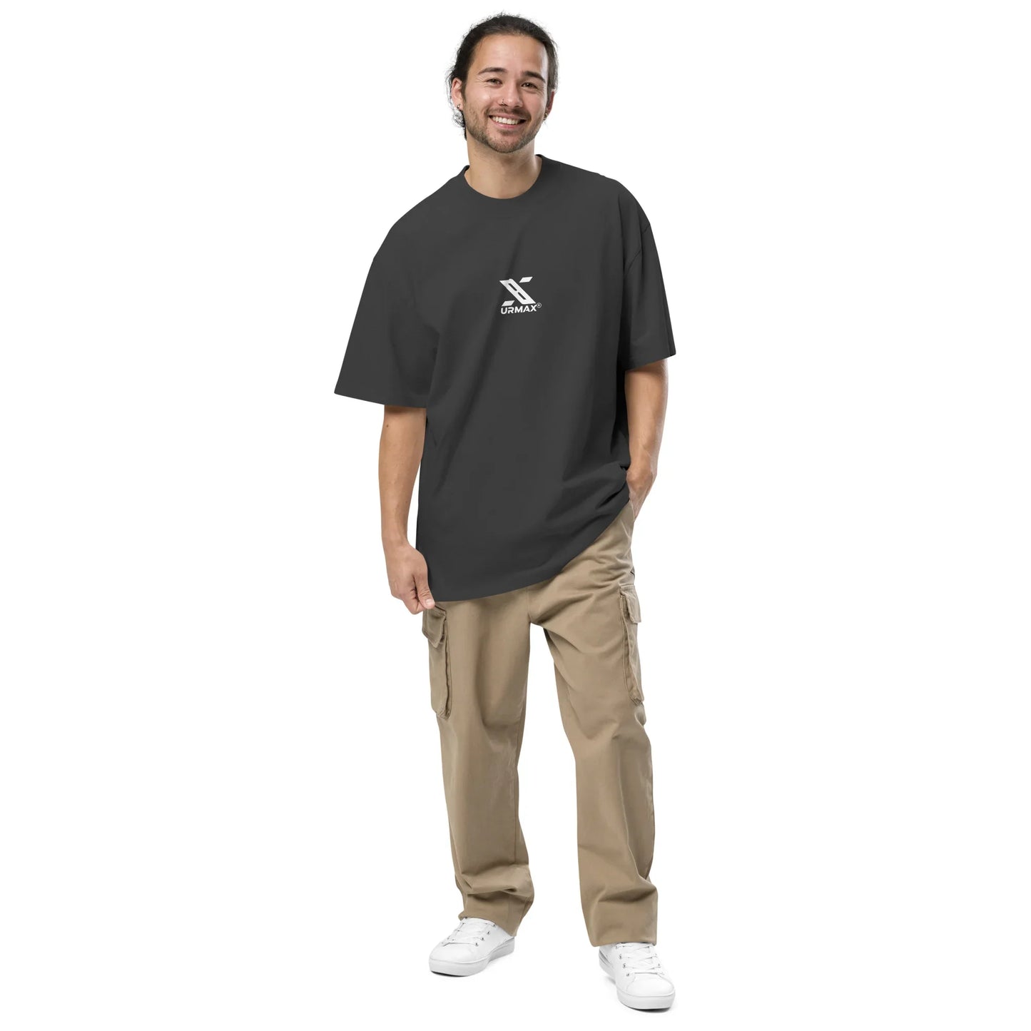 Man wearing oversized faded black urmax t-shirt with logo, beige cargo pants and white sneakers