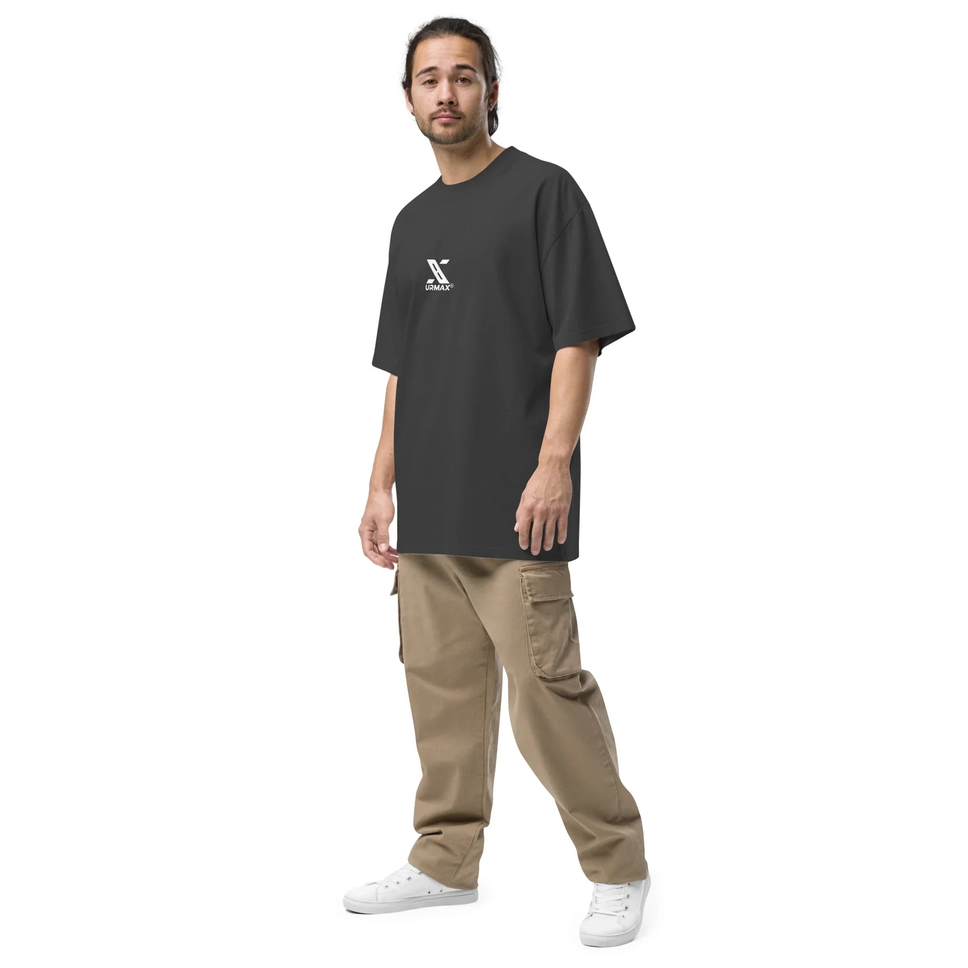 Man in oversized faded black urmax t-shirt, beige cargo pants, and white sneakers